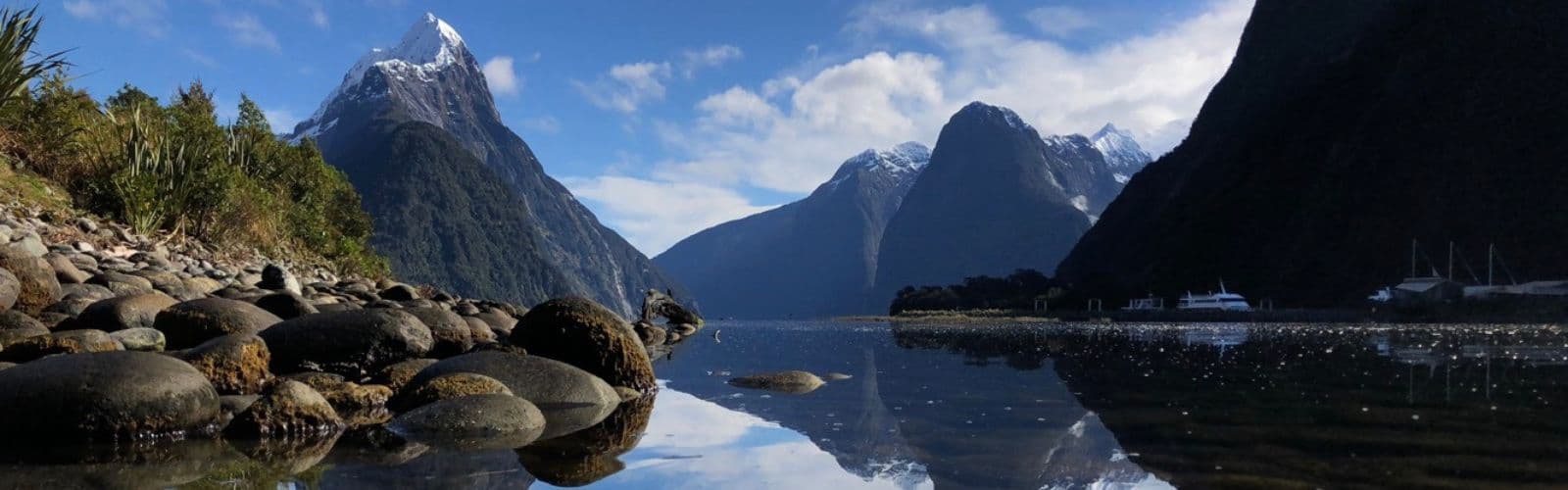 Snow-topped mountains are reflected in a lake on a sunny day. 